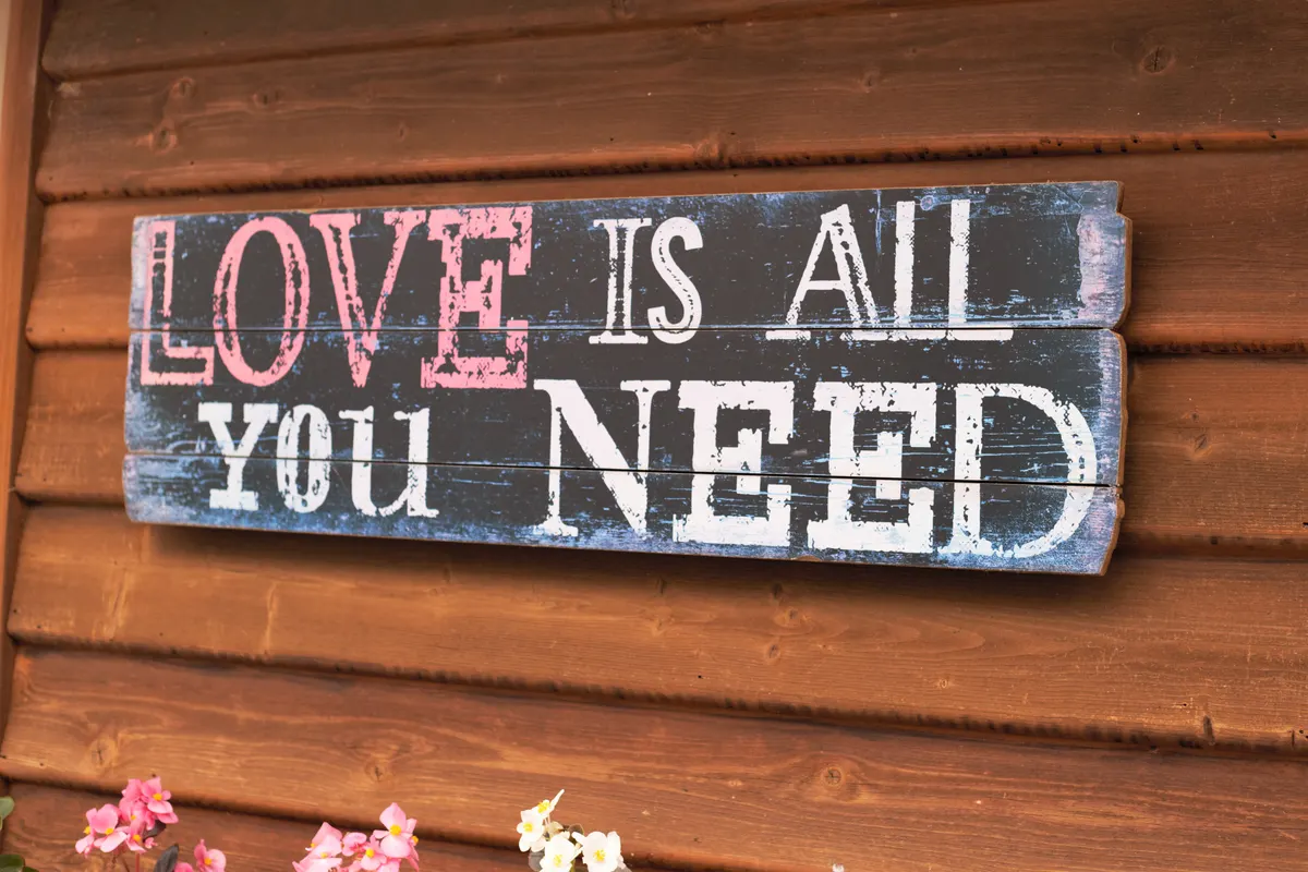 A rustic wooden sign reading “Love is all you need”
